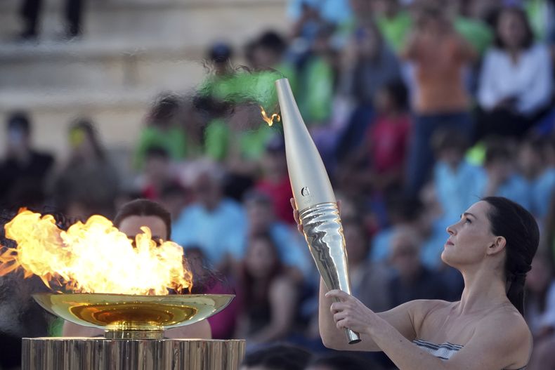 La actriz Mary Mina, como una sacerdotisa griega, sostiene una antorcha con la llama de los Juegos Olímpicos, el viernes 26 de abril de 2024, en el Estadio Panatenaico de Atenas, donde se celebraron los primeros Juegos Olímpicos de la actual era, en 1896. (AP Foto/Petros Giannakouris)