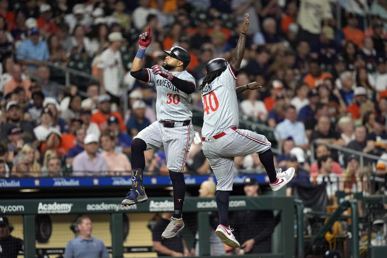 Carlos Santana (30), de los Mellizos de Minnesota, celebra con el coach de tercera base, Tommy Watkins (40), después de disparar jonrón en contra de los Astros de Houston durante la octava entrada del juego de béisbol del viernes 31 de mayo de 2024, en Houston. (AP Foto/David J. Phillip)
