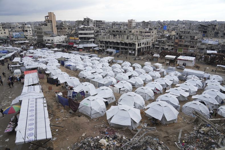 Un campamento de palestinos desplazados se encuentra al lado de viviendas y edificios destruidos en Ciudad de Gaza, en la Franja de Gaza, el sábado 1 de marzo de 2025. (AP Foto/Abdel Kareem Hana)