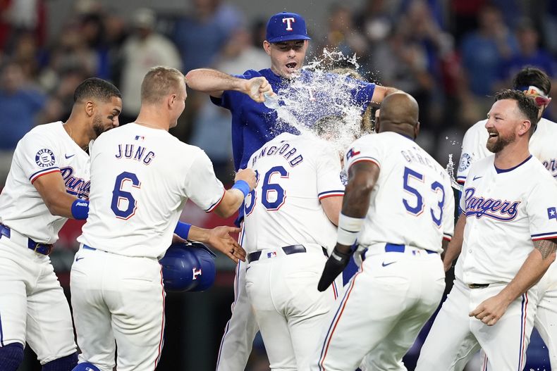 Cody Bradford de los Rangers de Texas baña a Wyatt Langford en la celebración del equipo tras el sencillo anotador de Langford en la novena ante los Piratas de Pittsburgh el miércoles 21 de agosto del 2024. (AP Foto/Tony Gutierrez)