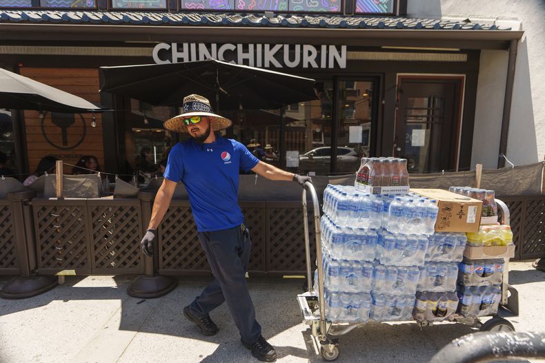 Un empleado lleva productos a un comercio en el distrito “Little Tokyo” de Los Ángeles, el 27 de julio de 2023.. (Foto AP /Damian Dovarganes)