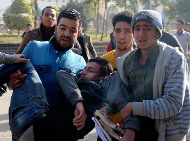 Un grupo de egipcios trata de salvar la vida de un estudiante de la Universidad al-Azhar gravemente herido por los enfrentamientos frente a la universidad en El Cairo, Egipto, el domingo 29 de diciembre de 2013. La universidad ha sido escenario de protest