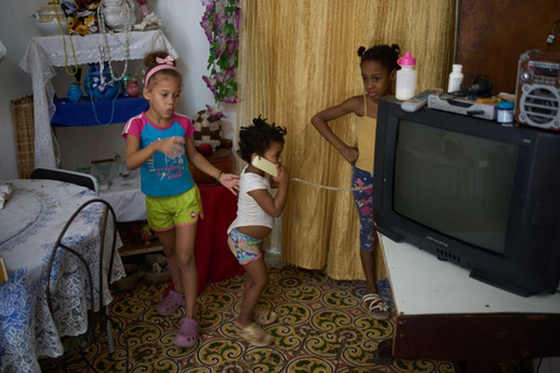 Edianet, a la izquierda, y su hermana Seinet, en el centro, juegan con una amiga en su casa en La Habana, Cuba, el miércoles 25 de marzo de 2026. (AP Foto/Ramón Espinosa)