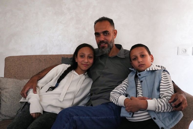 El técnico médico palestino Mohammed Abu Moussa, de 45 años, que fue liberado de detención israelí tras 20 meses, posa para una foto con sus hijos, Jourie y Hamid, en Deir al-Balah, Gaza, el sábado 18 de octubre de 2025. (AP Foto/Abdel Kareem Hana)