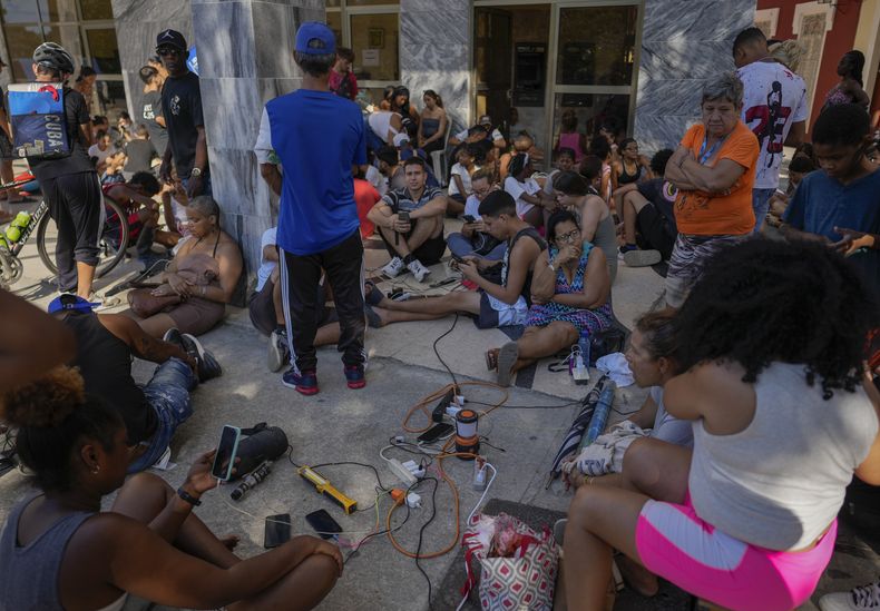 Residentes cargan sus dispositivos electrónicos en la calle durante un apagón nacional en La Habana, el sábado 15 de marzo de 2025. (AP Foto/Ramon Espinosa)