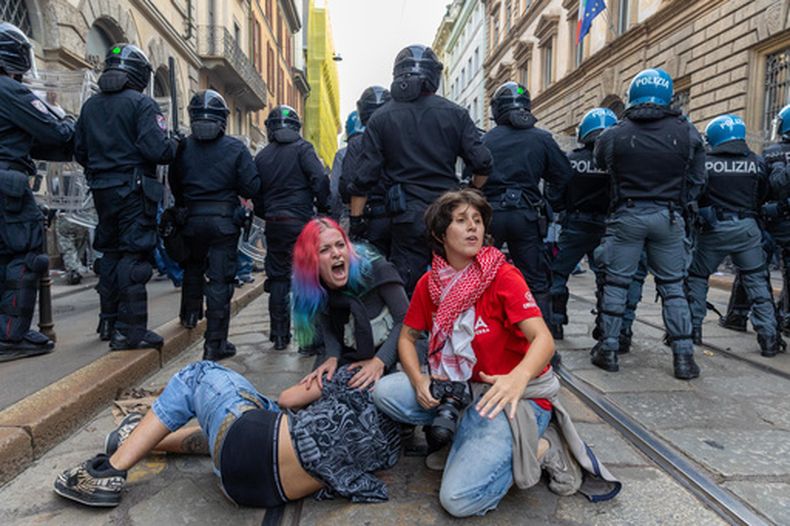 Manifestantes se refugian detrás de la policía tras el estallido de disturbios en una protesta contra el alto costo de vida, en Milán, Italia, el sábado 17 de octubre de 2026. (Stefano Porta/LaPresse vía AP)