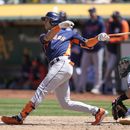 El dominicano Jeremy Peña, de los Astros de Houston, conecta un doblete adelante del cátcher Shea Langeliers, de los Atléticos de Oakland, en el juego del sábado 27 de mayo de 2023 (AP Foto/Jeff Chiu)