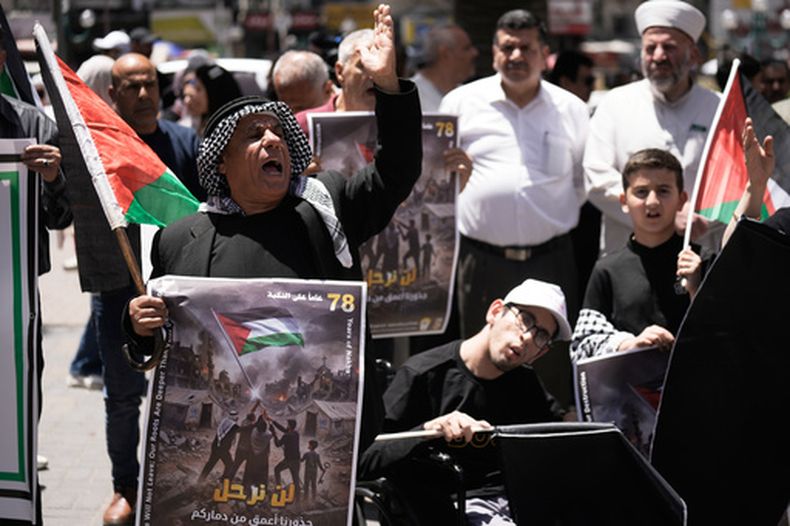 Un grupo de palestinos grita consignas en una marcha previa al 78vo aniversario de lo que denominan la Nakba, o catástrofe, en la ciudad de Nablus, en Cisjordania, el lunes 11 de mayo de 2026. El letrero en árabe dice, “No nos iremos; nuestras raíces son más profundas que su destrucción”. (AP Foto/Majdi Mohammad)