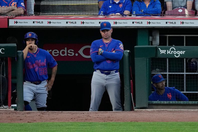 El mánager de los Mets de Nueva York Carlos Mendoza (centro) desde la cueva durante el juego contra los Rojos de Cincinnati, el lunes 15 de junio de 2026, en Cincinnati. (AP Foto/Carolyn Kaster)
