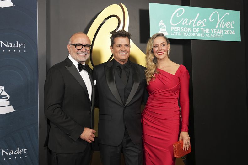 Carlos Vives, Persona del Año de la Academia Latina de la Grabación, posa con su esposa Claudia Elena Vázquez y el director ejecutivo de la academia Manuel Abud, el miércoles 13 de noviembre de 2024, en Miami Beach, Florida. (Foto AP/Lynne Sladky)