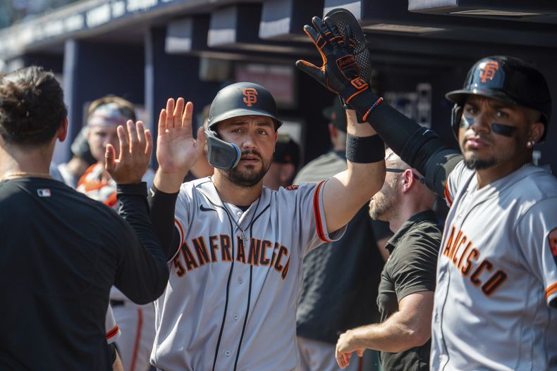 Michael Conforto, centro, de los Gigantes de San Francisco, es felicita a Johan Camargo y a otros compañeros de equipo después de anotar en la novena entrada en el juego de béisbol en contra de los Bravos de Atlanta, el domingo 20 de agosto de 2023, en Atlanta. (AP Foto/Hakim Wright Sr.)