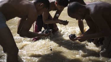 Venezolanos pobres recurren a buscar chatarra en un río