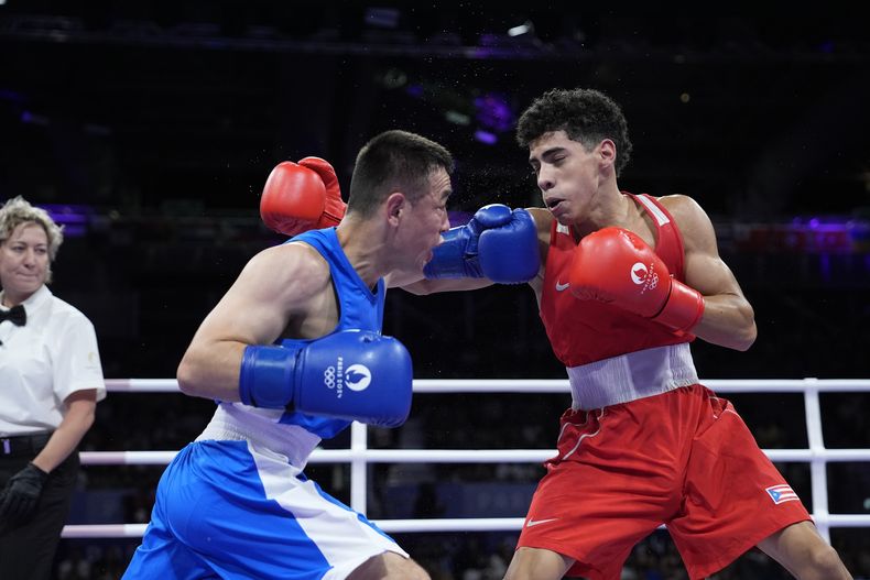 El puertorriqueño Juanma López, a la derecha, en su duelo de peso mosca ante el uzbeko Hasanboy Dusmatov, el martes 30 de julio de 2024, en Villepinte, Francia. (AP Foto/John Locher)
