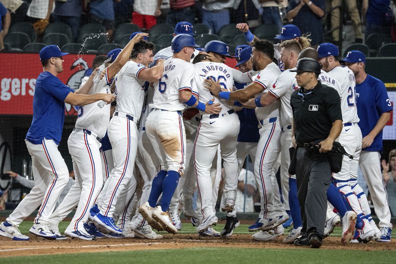 Wyatt Langford (36), de los Rangers de Texas, celebra con sus compañeros de equipo en el plato después de conectar un grand slam ante el lanzador relevista de los Yankees de Nueva York, Clay Holmes, durante la novena entrada de un juego de béisbol el martes 3 de septiembre de 2024, en Arlington, Texas. Leody Taveras, Josh Smith y Marcus Semien anotaron en la jugada. (AP Foto/Jeffrey McWhorter)