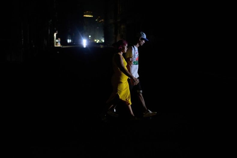 Dos personas cruzan una calle durante un apagón el 4 de marzo de 2026, en La Habana. (AP foto/Ramón Espinosa)