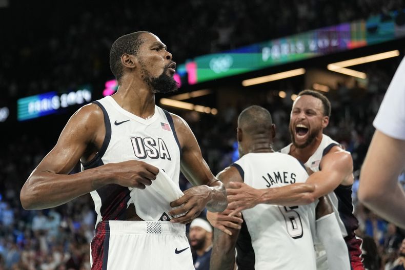 Los estadounidenses Kevin Durant (7), LeBron James (6) y Stephen Curry (4) celebran la victoria ante Serbia en el baloncesto de los Juegos Olímpicos de París, el jueves 24 de agosto de 2024. (AP Foto/Mark J. Terrill)