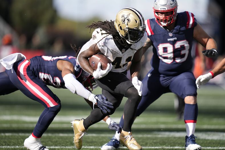 Alvin Kamara (41), corredor de los Saints de Nueva Orleans, corre ante la presión del safety Kyle Dugger, izquierda, y el defensive end Lawrence Guy Sr., derecha, de los Patriots de Nueva Inglaterra, durante la segunda mitad del juego de la NFL, el domingo 8 de octubre de 2023, en Foxborough, Massachusets. (AP Foto/Charles Krupa)