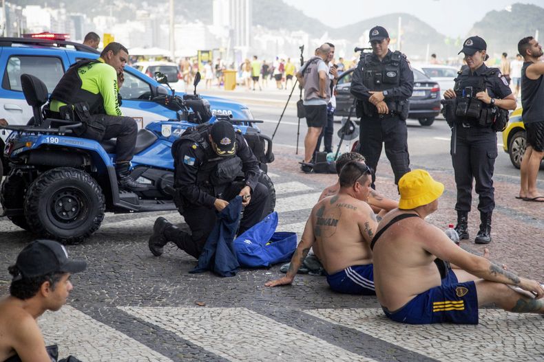 Policías inspeccionan las mochilas de fanáticos argentinos de Boca Juniors mientras hacen un recorrido por la playa de Copacabana un día antes de la Final de la Copa Libertadores en Río de Janeiro, Brasil, el viernes 3 de noviembre de 2023. (AP Foto/Bruno Kaiuka)