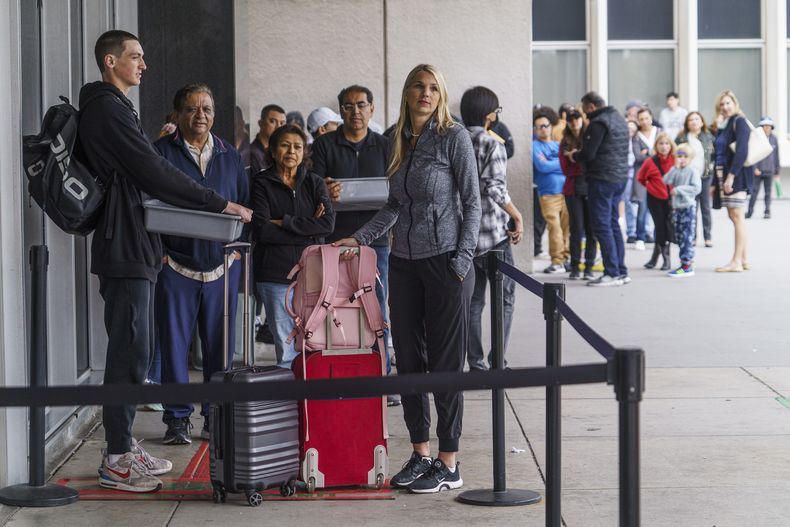 Marni Larsen y su hijo Damon Rasmussen, de Holladay, Utah, esperan en fila para recibir sus pasaportes en Los Ángeles el 14 de junio de 2023. (Foto AP /Damian Dovarganes)