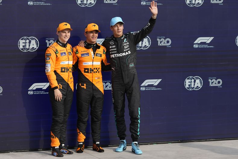 Lando Norris de McLaren celebra tras quedarse con la primera posición en la parrilla, junto a su compañero Oscar Piastri, que saldrá segundo y George Russell de Mercedes, quien saldrá tercero en el Gran Premio de Italia tras la calificación del sábado 31 de agosto del 2024. (AP Foto/Luca Bruno)