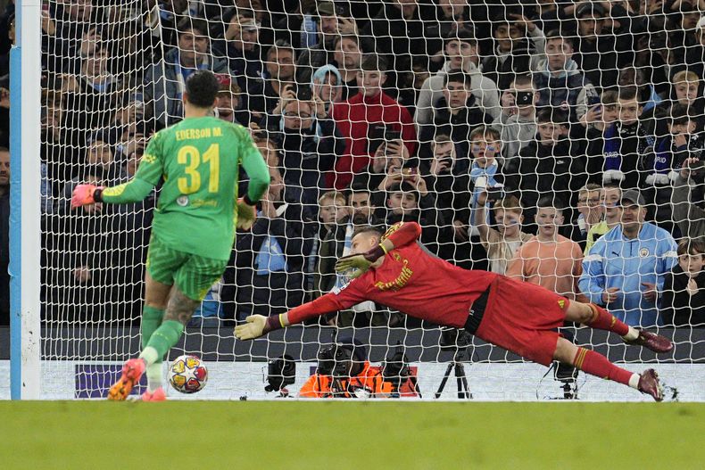 El portero del Real Madrid Andriy Lunin se lanza para intentar detener el gol de Ederson del Manchester City en el duelo de vuelta de los cuartos de final de la Liga de Campeones el miércoles 17 de abril del 2024. (AP Foto/Dave Shopland)