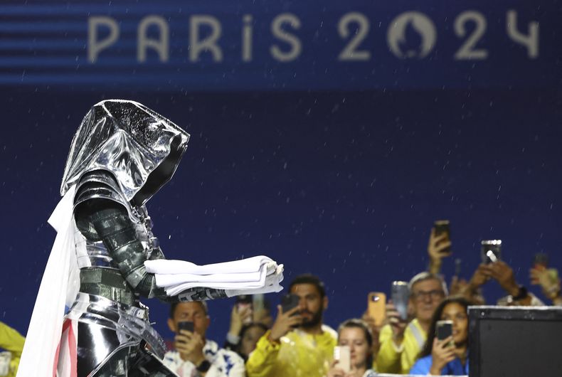 Una mujer porta la bandera olímpica en el Trocadero, durante la ceremonia inaugural de los Juegos de París, el viernes 26 de julio de 2024 (Stephanie Lecocq/Pool Photo via AP)