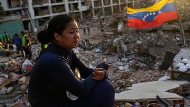 Estefany Landaez permanece sentada entre los escombros de un edificio esperando encontrar a sus dos hijos tras los terremotos en La Guaira, Venezuela, el domingo 12 de julio de 2026. (AP Foto/Ariana Cubillos)