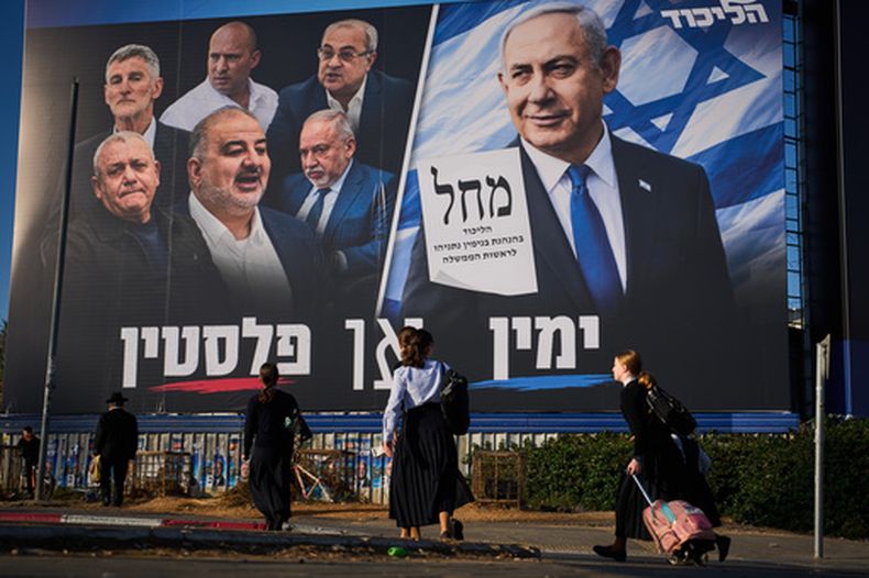 ARCHIVO – Varias personas caminan frente a un cartel de campaña del partido Likud en el que aparece el primer ministro Benjamin Netanyahu junto con líderes de oposición con el eslogan en hebreo “Derecha o Palestina”, antes de la elección general en Israel, en Beni Brak, Israel, el domingo 18 de octubre de 2026. (AP Foto/Oded Balilty, Archivo)