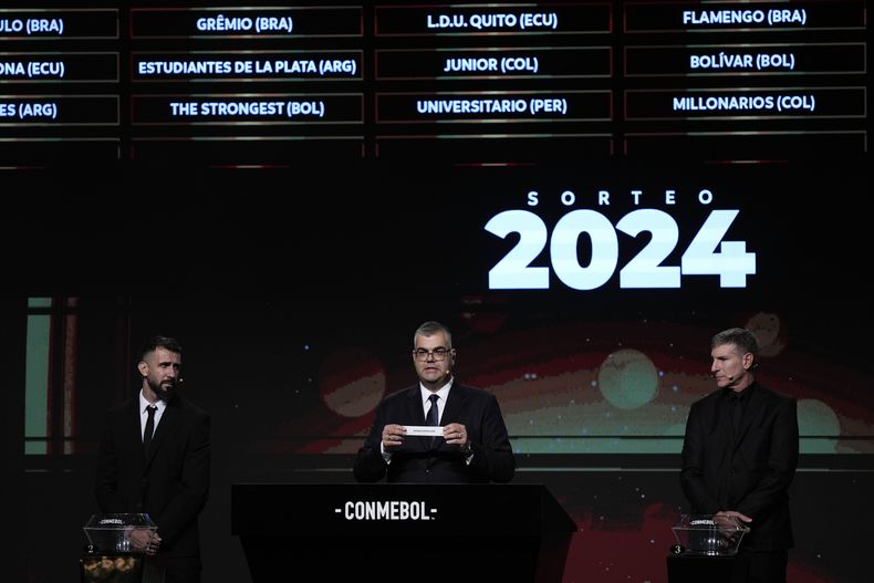 Frederico Nantes, centro, director de competencias de CONMEBOL, presenta el papel con el nombre de Rosario Central, de Argentina, durante el sorteo de la Copa Libertadores, en Luque, Paraguay, el lunes 18 de marzo de 2024. (AP Foto/Jorge Saenz)