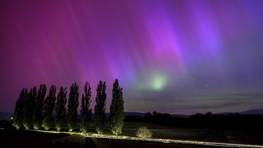 En esta fotografía de larga exposición, un auto circula por una carretera mientras las auroras boreales iluminan el cielo nocturno en Daillens, Suiza, el 11 de mayo de 2024. (Laurent Gillieron/Keystone vía AP)