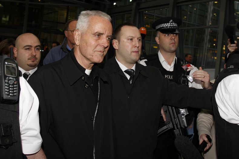 ARCHIVO – El obispo Richard Williamson, al frente, izquierda, es escoltado fuera del aeropuerto de Heathrow por policías y agentes de seguridad tras llegar en un vuelo desde Argentina, en Londres, el miércoles 25 de febrero de 2009. (AP Foto/Kirsty Wigglesworth, Archivo)