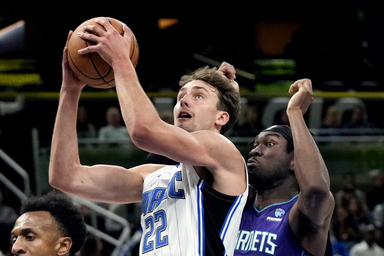 Franz Wagner (22), del Magic de Orlando, se alista para encestar frente a Mark Williams, de los Hornets de Charlotte, derecha, durante la primera mitad del juego de baloncesto de la NBA, el domingo 26 de noviembre de 2023, en Orlando, Florida. (AP Foto/John Raoux)