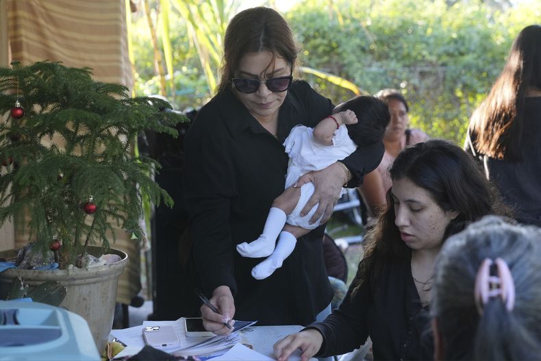 La defensora de inmigrantes, Nora Sandigo, firma unos papeles de custodia para niños nacidos en Estados Unidos cuyos padres se encuentran en el país de manera ilegal, el domingo 2 de febrero de 2025, en Homestead, Florida. (AP Foto/Marta Lavandier)