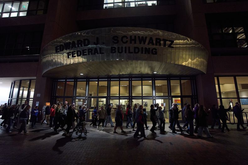 Personas se reúnen para llevar a cabo una vigilia y procesión en un tribunal federal en donde aseguran que agentes federales retienen a inmigrantes en el sótano de la instalación, el jueves 13 de noviembre de 2025, en San Diego. (AP Foto/Gregory Bull)