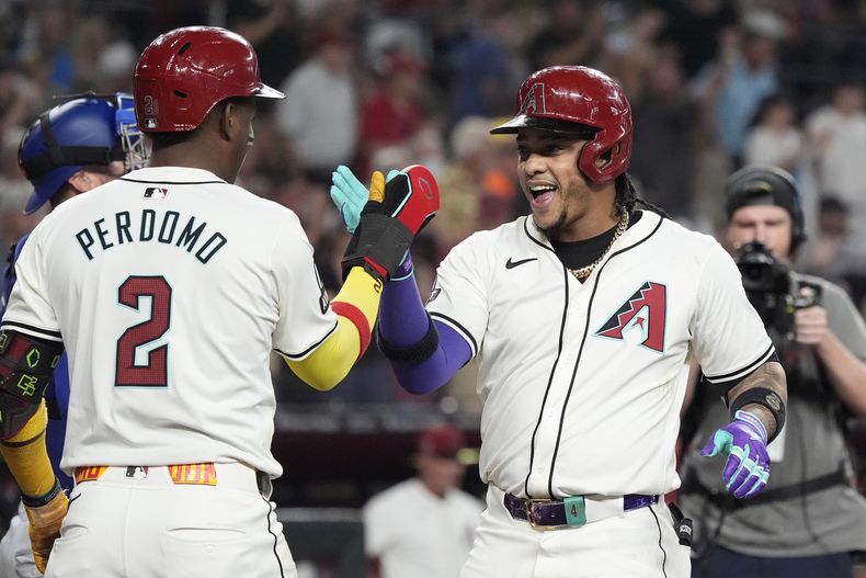 El dominicano Ketel Marte, de los Diamondbacks de Arizona, festeja con su compatriota y compañero Geraldo Perdomo, tras conectar un jonrón ante los Rangers de Texas, el miércoles 11 de septiembre de 2024 (AP Foto/Ross D. Franklin)