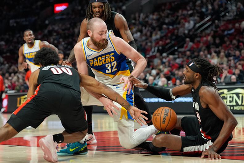 Jay Huff (32), de los Pacers de Indiana, busca un balón suelto entre Scoot Henderson (00) y Jerami Grant, derecha, de los Trail Blazers de Portland, durante la segunda mitad del partido de baloncesto de la NBA, el domingo 8 de marzo de 2026, en Portland, Oregon. (AP Foto/Jenny Kane)