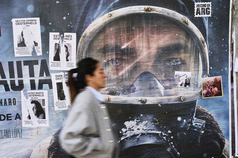 Un anuncio publicitario de la serie de Netflix El Eternauta cubierto parcialmente por carteles del autor del cómic de ciencia ficción Héctor Oesterheld y sus hijas, quienes fueron víctimas de desaparición forzada durante la dictadura militar argentina (1976-1983), el martes 6 de mayo de 2025, en Buenos Aires. (AP Foto/Rodrigo Abd)