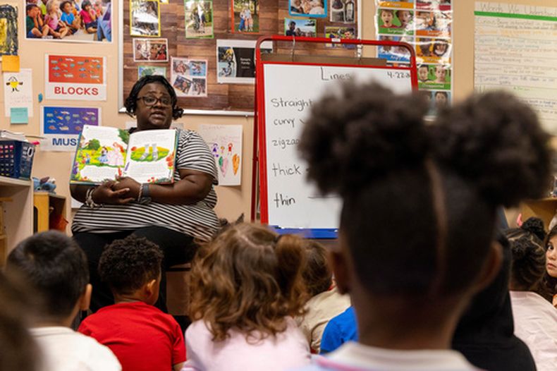La maestra asistente Yolanda Maheia lee un libro ante un grupo de estudiantes de preescolar en The Capitol Hill Child Enrichment Center, el miércoles 22 de abril de 2026, en Atlanta. (AP Foto/Alyssa Pointer)