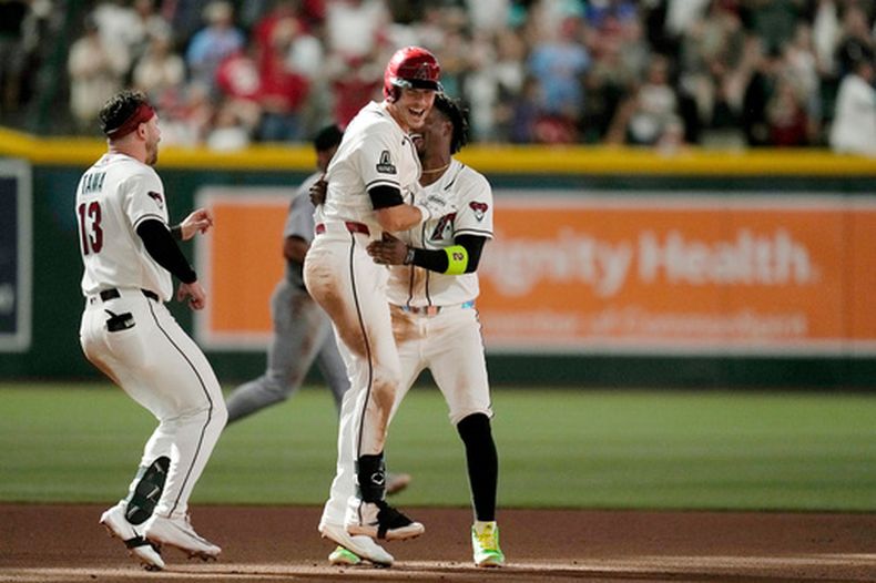 Max Kepler, centro, de los Diamondbacks de Arizona, celebra con Geraldo Perdomo, derecha, y Tim Tawa (13), su doble productor con el que su equipo dejó tendido en el terreno a los Cardenales de San Luis en la décima entrada del juego de béisbol de Grandes Ligas, el domingo 19 de julio de 2026, en Phoenix. (AP Foto/Ross D. Franklin)
