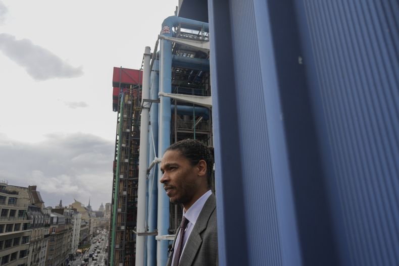 El director de seguridad del Cetro de Arte Pompidou, Alexandre Aumis, de pie con el 1.500o mosaico del artista francés Invader en la ciudad, arriba al centro, en París, el viernes 1 de marzo de 2024. Invader, uno de los artistas franceses más internacionales, ha pegado mosaicos en las paredes de la capital francesa, el mundo e incluso los ha llevado a la Estación Espacial Internacional. (Foto AP/Thibault Camus)