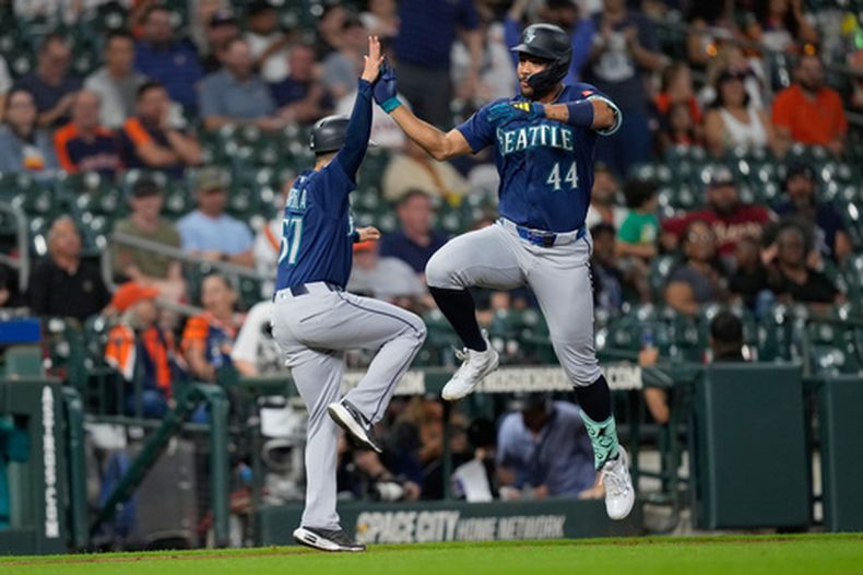 Julio Rodríguez (44), de los Marineros de Seattle, celebra con el coach de tercera, Carlos Cardoza (57), después de disparar un jonrón contra los Astros de Houston durante la tercera entrada del juego de béisbol de Grandes Ligas, el lunes 11 de mayo de 2026, en Houston. (AP Foto/David J. Phillip)