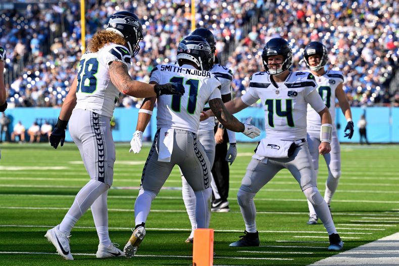 Jaxon Smith-Njigba (11), wide receiver de los Seahawks de Seattle, celebra la recepción de su pase de touchdown con el quarterback Sam Darnold (14) durante la segunda mitad de un juego de fútbol americano de la NFL contra los Titans de Tennessee, el domingo 23 de noviembre de 2025, en Nashville, Tennessee. (AP Photo/John Amis)