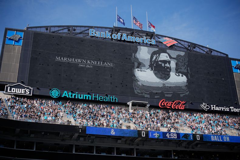 Aficionados participan en un minuto de silencio por la muerte de Marcus Kneeland de los Cowboys de Dallas antes del juego entre los Panthers de Carolina y Saints de Nueva Orleans el domingo 9 de noviembre del 2025. (AP Foto/Jacob Kupferman)