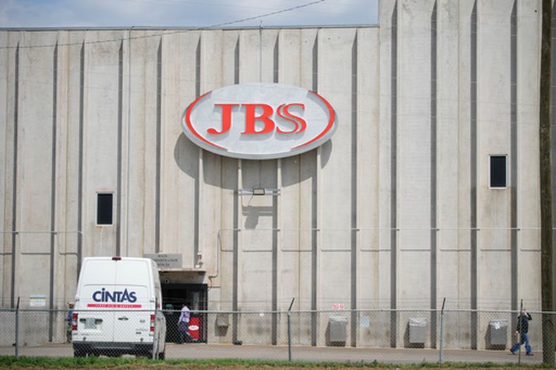 Empleados caminan frente a la entrada de la procesadora de carne JBS, el 23 de julio de 2021, en Greeley, Colorado. (AP Foto/David Zalubowski, Archivo)