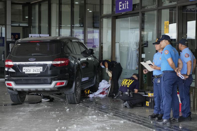 Trabajadores de emergencias trabajan en el lugar después de que un vehículo chocara contra la puerta de salidas en la Terminal 1 del Aeropuerto Internacional de Manila, en Manila, Filipinas, el domingo 4 de mayo de 2025. (AP Foto/Aaron Favila)