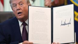 El presidente Donald Trump sostiene una orden ejecutiva recién firmada en el Despacho Oval de la Casa Blanca, el martes 31 de marzo de 2026, en Washington. (AP Foto/Alex Brandon)
