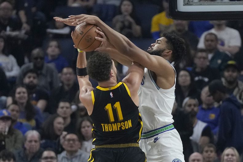 Karl-Anthony Towns, derecha, de los Timberwolves de Minnesota, bloquea un tiro de Klay Thompson (11), de los Warriors de Golden State, durante la primera mitad del juego de baloncesto de la NBA, en San Francisco, el domingo 12 de noviembre de 2023. (AP Foto/Jeff Chiu)
