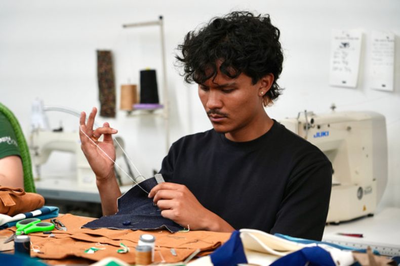 Jesse Sanchez practica la costura durante un taller de reparación de ropa en una tienda Levis en el centro de San Francisco, el miércoles 22 de julio de 2026. (AP Foto/Terry Chea)