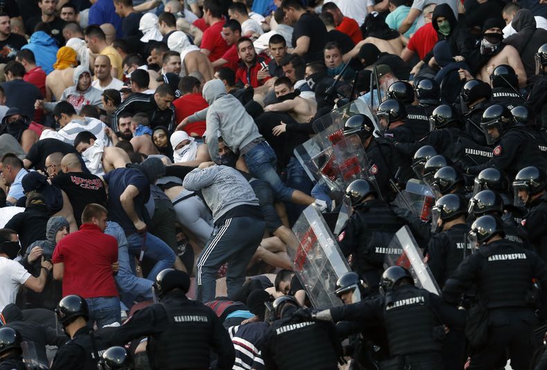 ARCHIVO - En esta foto del 16 de abril de 2016, policías antimotines chocan con hinchas del Estrella Roja durante un partido de la Liga Serbia ante el Partizan en Belgrado (AP Foto/Darko Vojinovic, archivo)