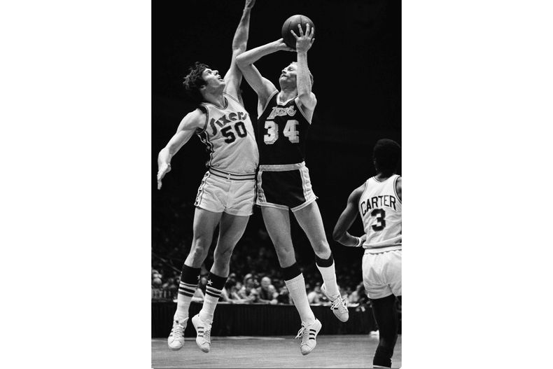 ARCHIVO - Foto del 9 de enero de 1975, Stan Love de los Lakers de Los Ángeles intenta anotar mientras lo defiende Steve Mix de los 76ers de Filadelfia. (AP Foto/Rusty Kennedy, Archivo)